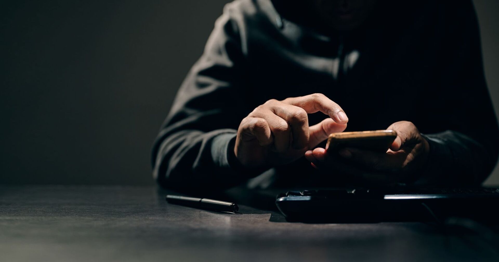 Ein Bursche tippt in Dunkeln etwas in sein Smartphone.