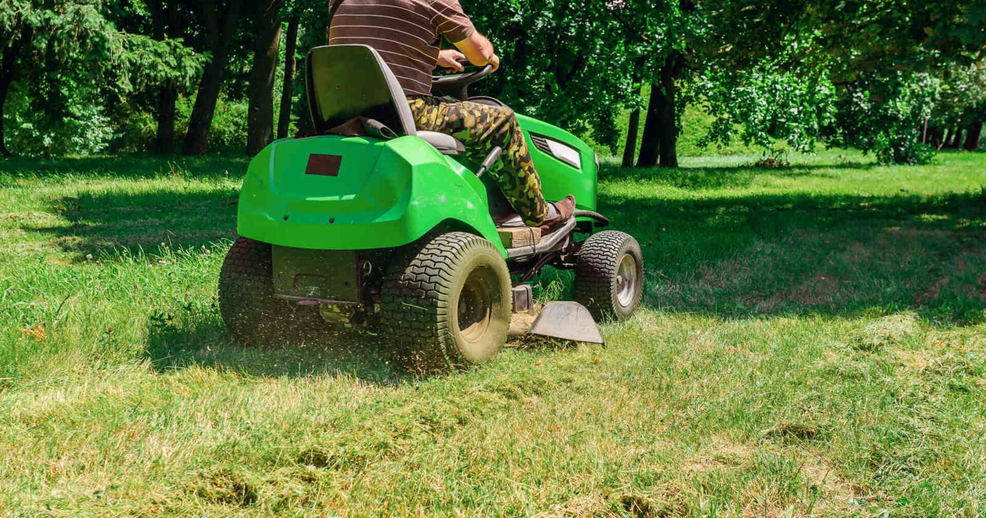 Ein Mann sitzt auf einem Rasenmäher-Traktor