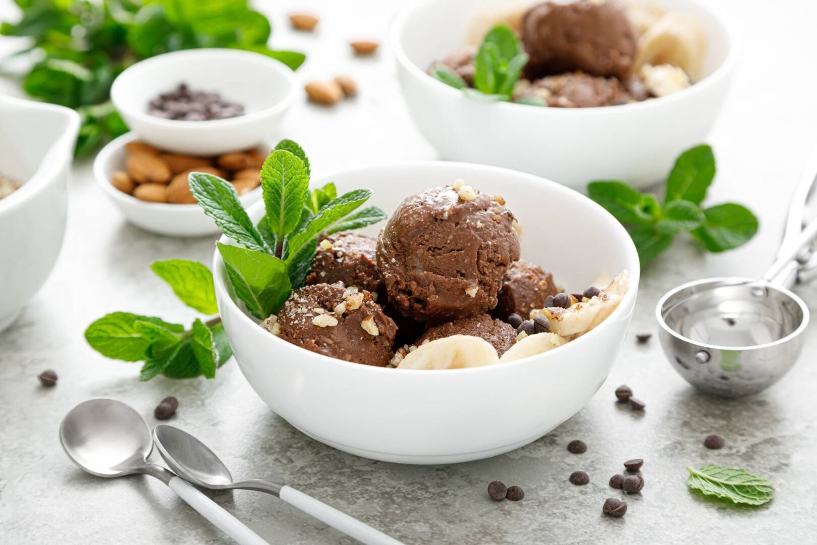 Keramikschale mit Schokoladeneis, dekoriert mit frischen Bananen und Minzeblättern
