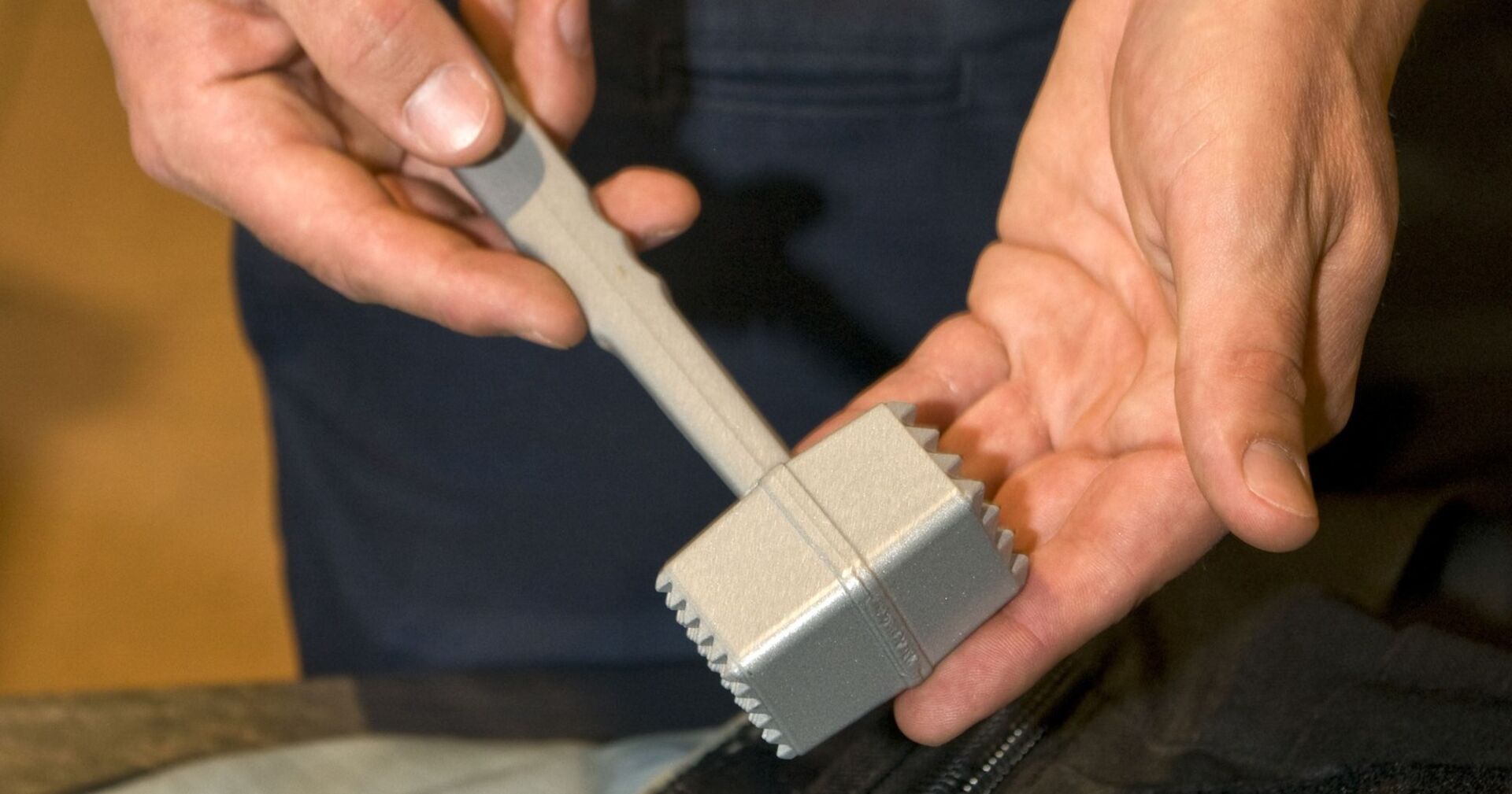 Ein Polizist hält einen Fleischklopfer in die Kamera.