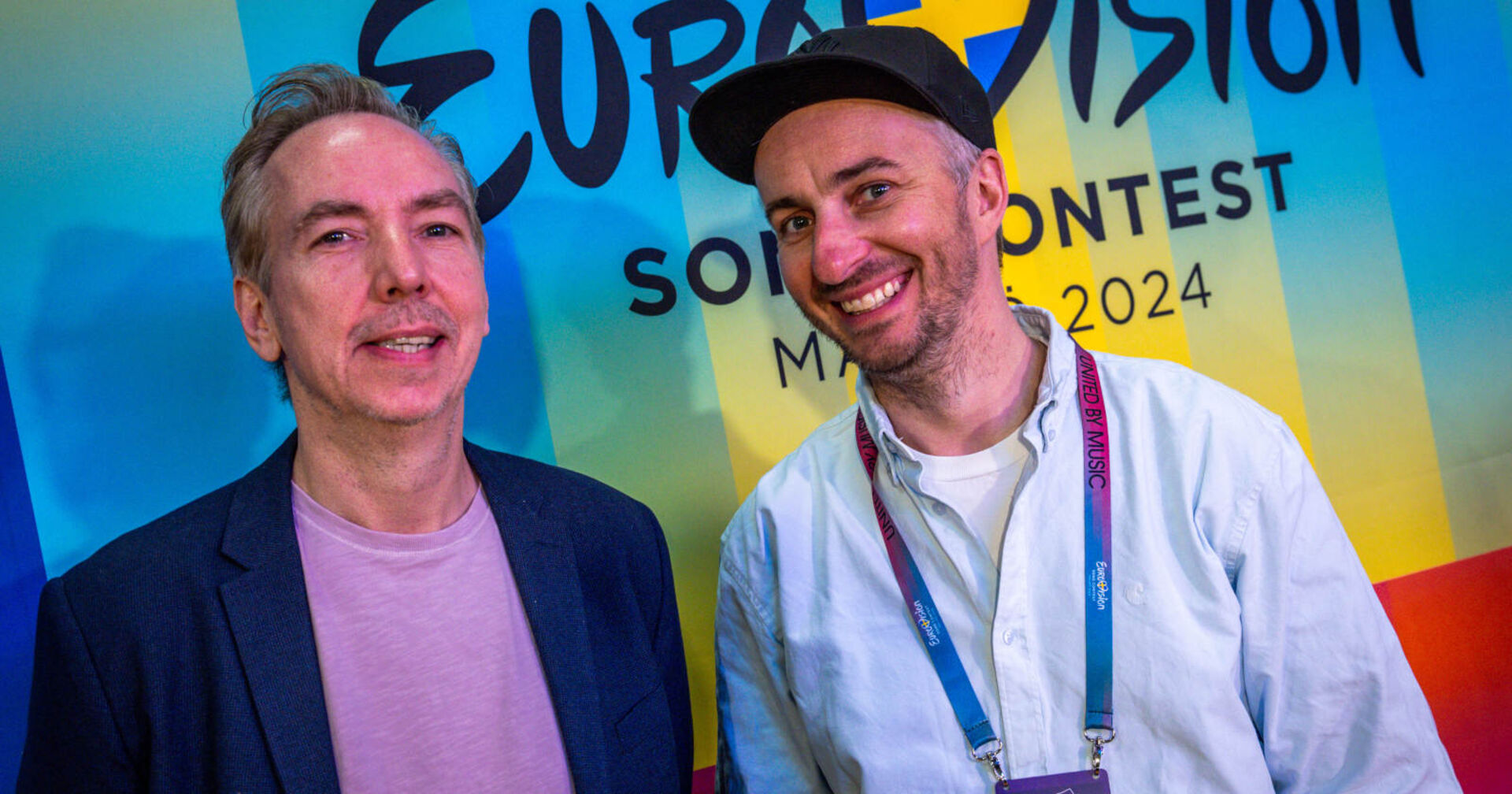 Zwei Männer stehen nebeneinander und grinsen in die Kamera