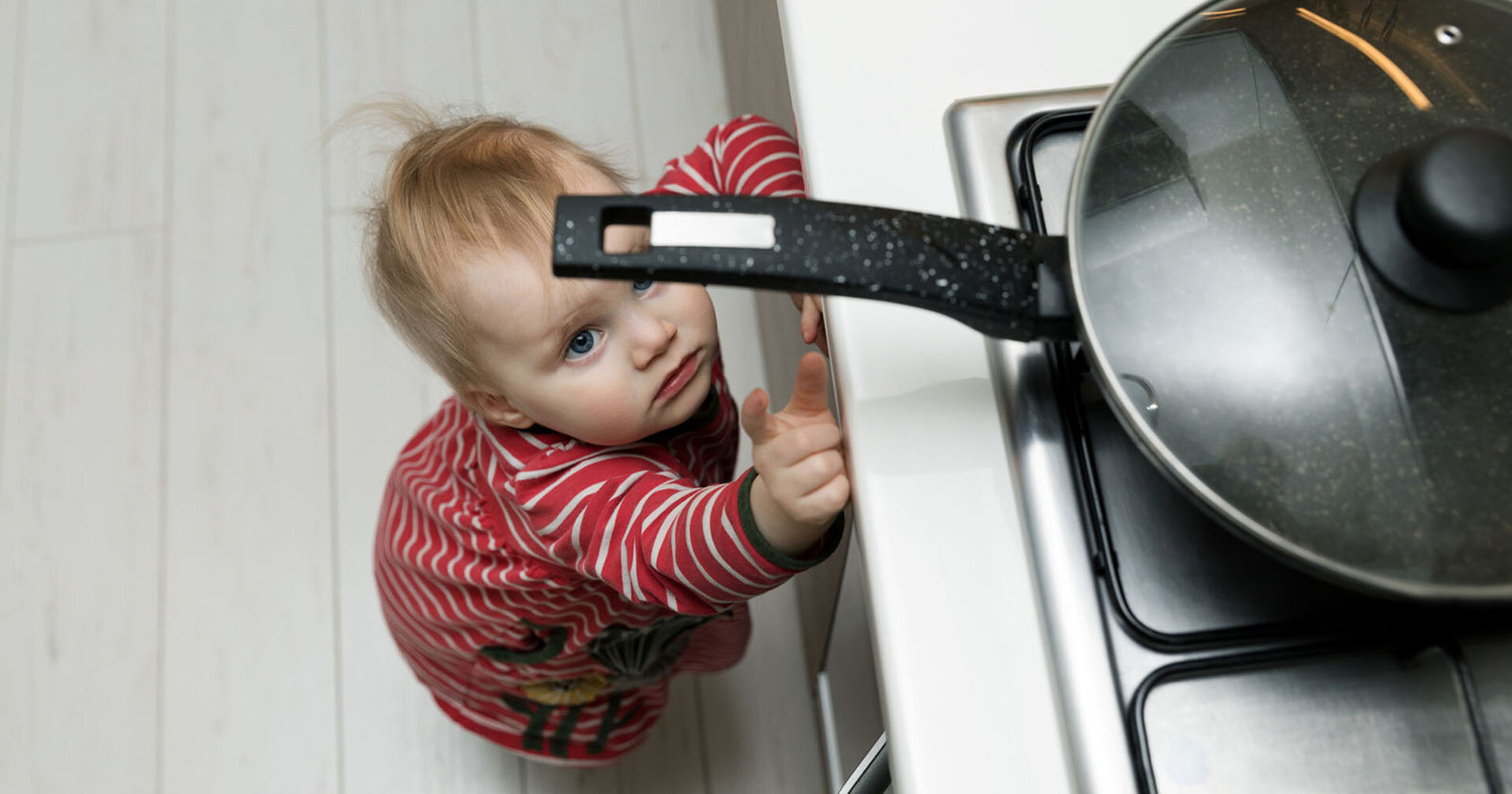 Kind greift nach Pfanne am Herd | Credit: iStock.com/ronstik