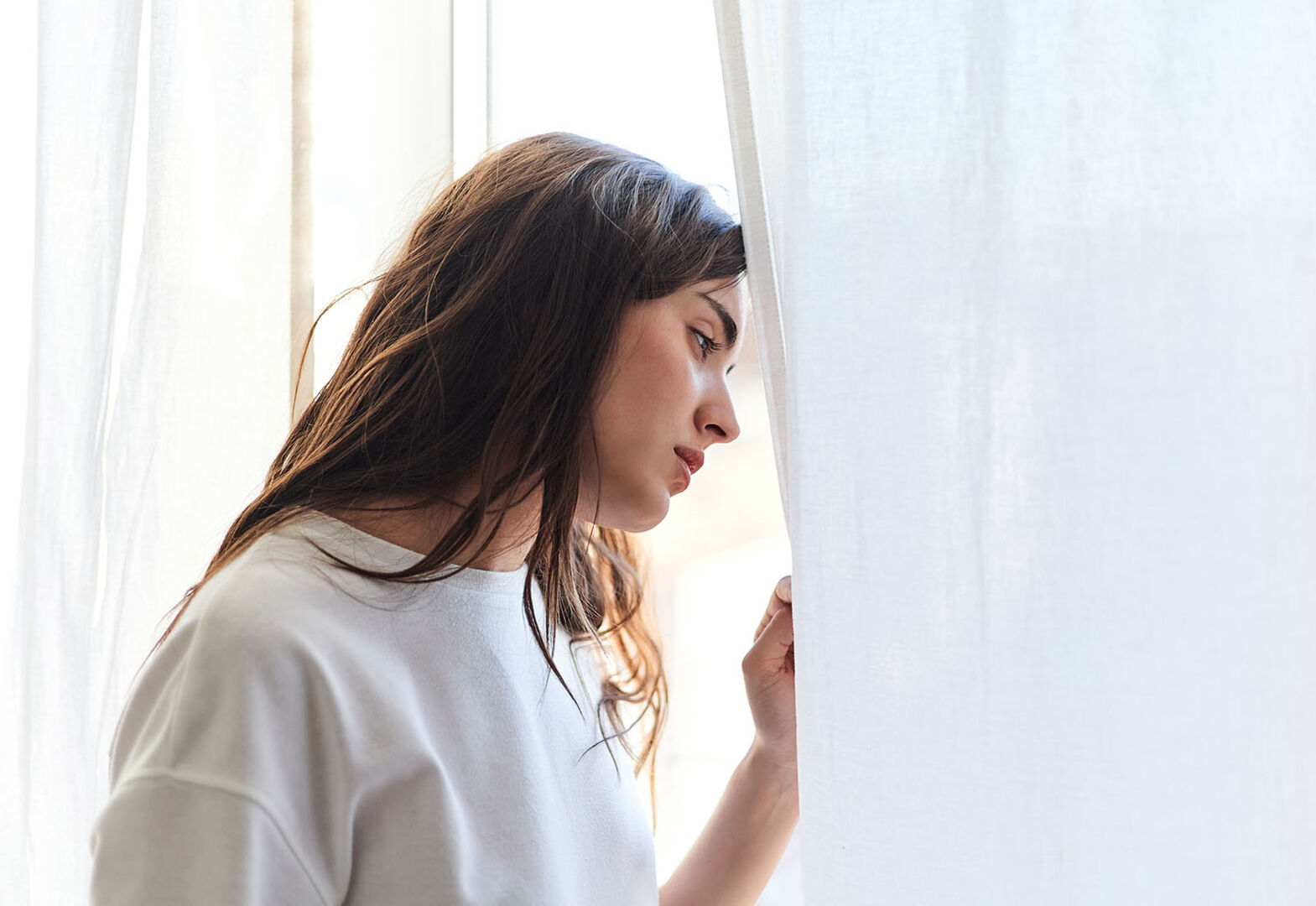 Frau schaut nachdenklich aus einem Fenster | Credit: iStock.com/Javi Sanz