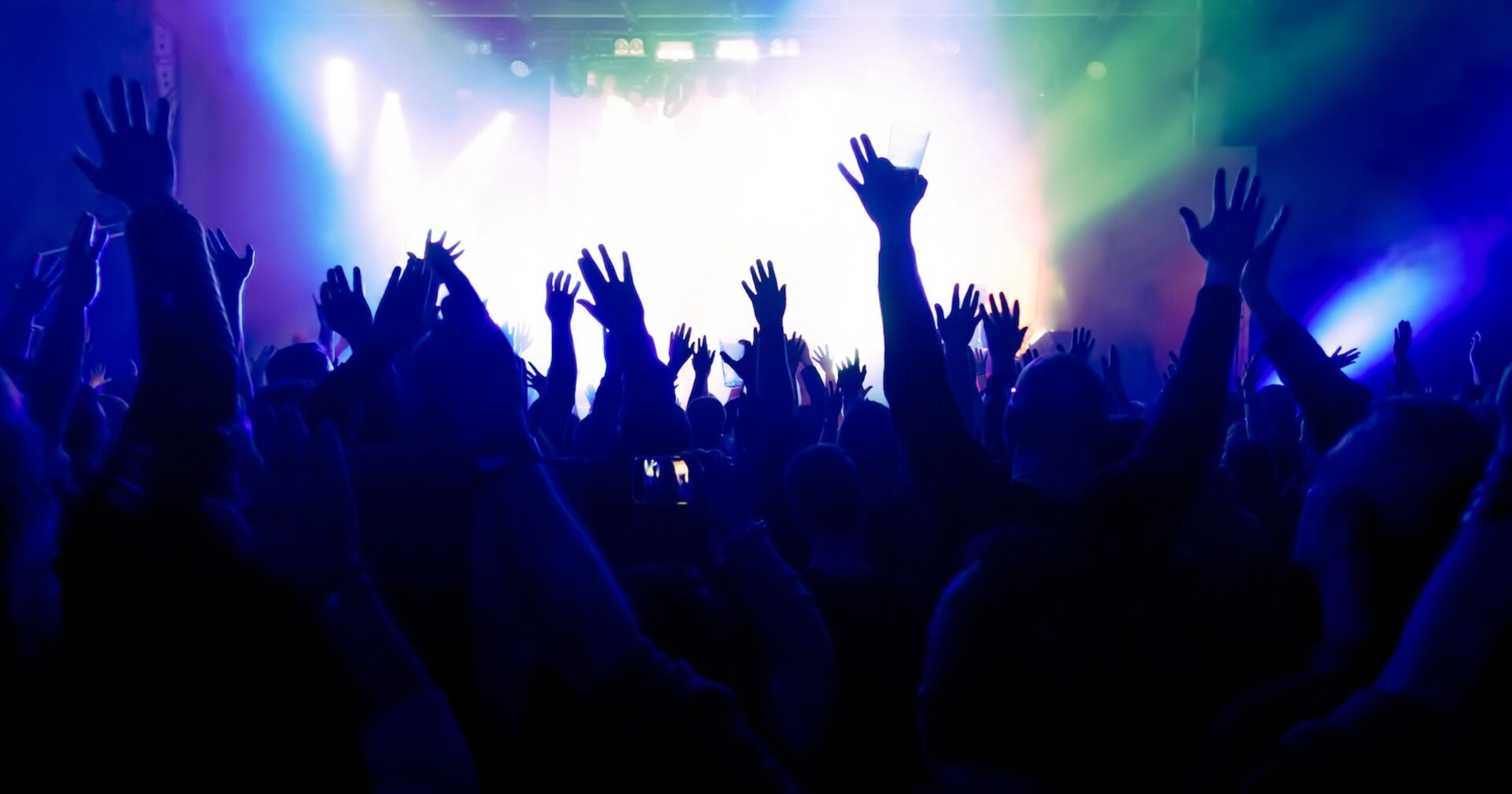 Menschen feiern in einem Club und strecken die Hände in die Höhe