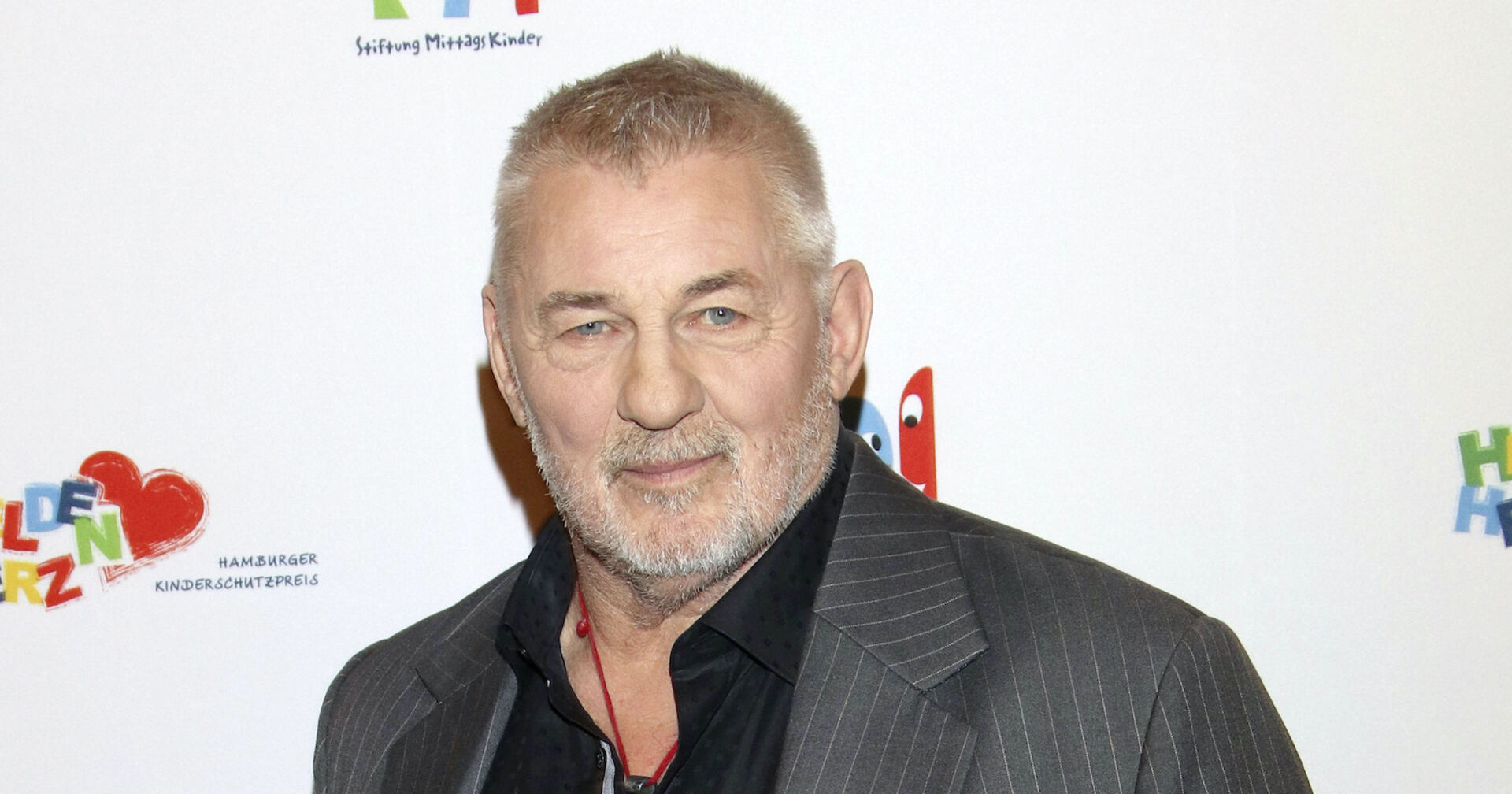 Heinz Hoenig mit einem grauen Sakko und einem schwarzen Hemd.