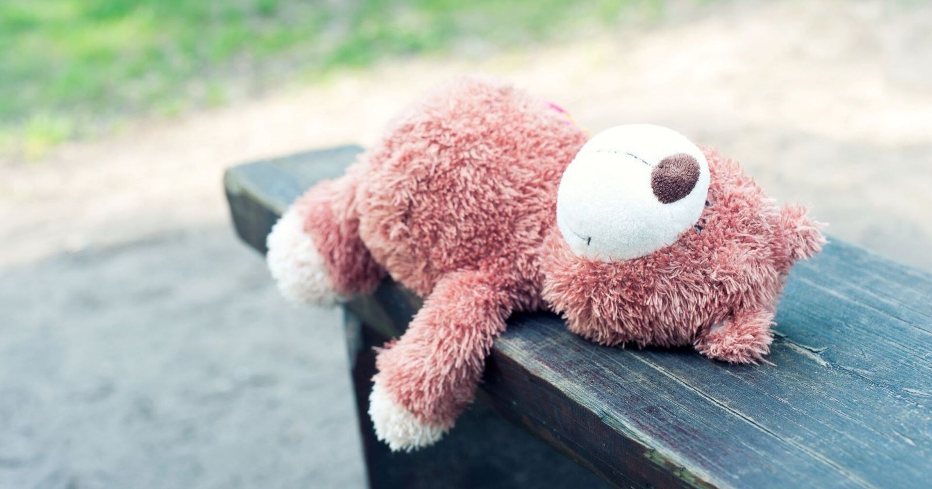 Ein einsamer Teddybär liegt auf einer Bank.