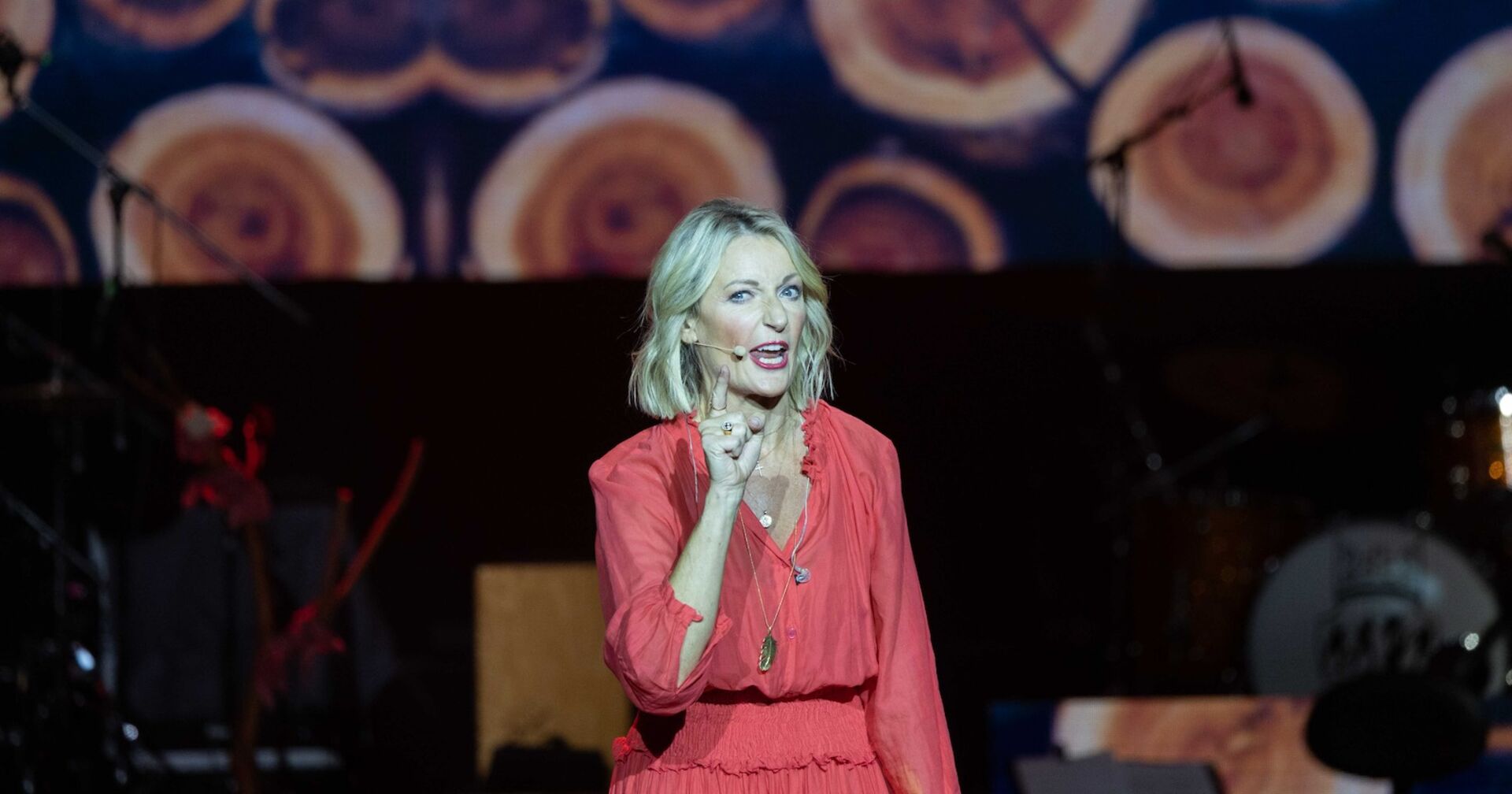 Monika Gruber in einem roten Kleid auf der Bühne.