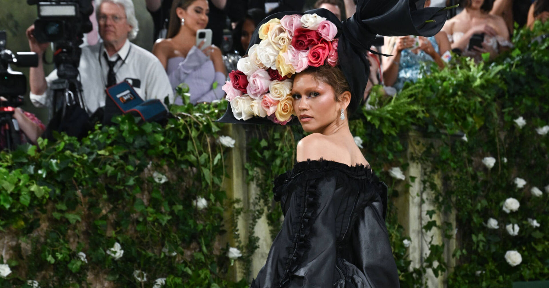 Frau in schwarzem Kleid mit großem Blumen-Hut