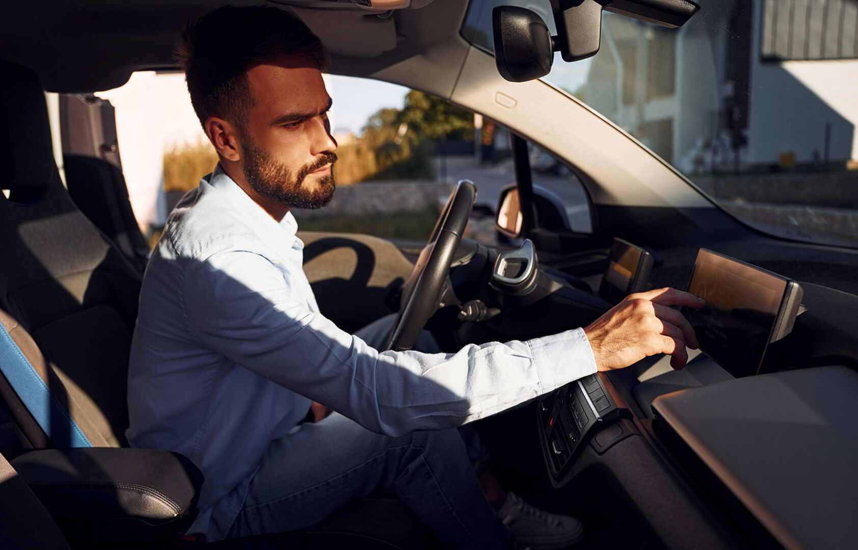 Junger Mann hinter dem Steuer seines Elektroautos | Credit: iStock.com/standret