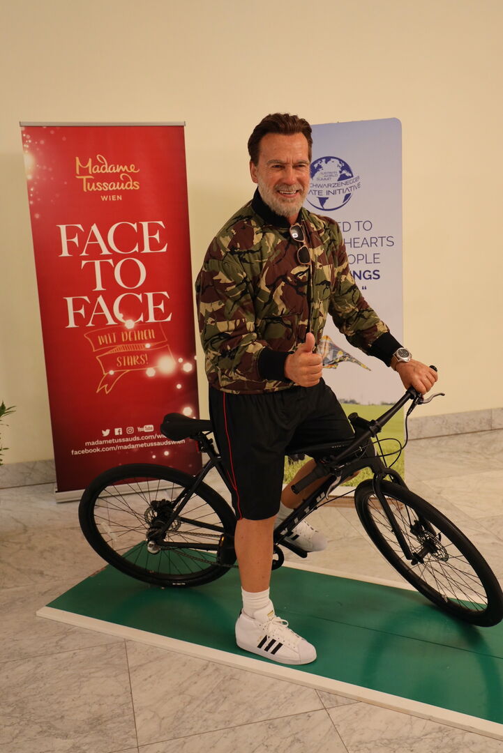 Arnold Schwarzenegger als Wachsfigur auf dem Fahrrad.