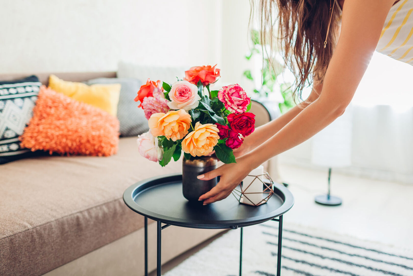 Frau stellt Blumenstrauß auf einen Tisch | Credit: iStock.com/Maryviolet