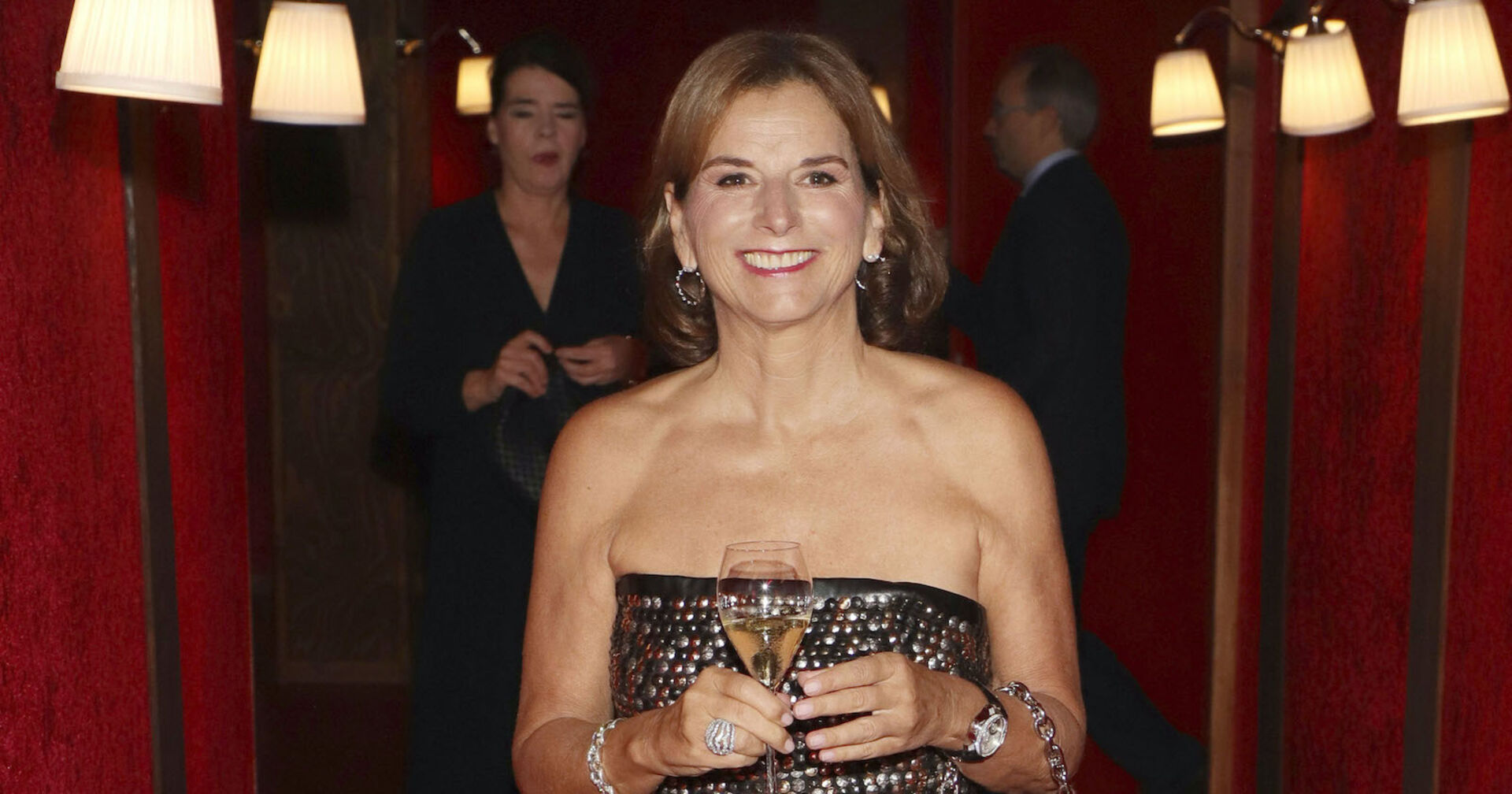 Claudia Obert mit ienem Champagner Glas und einem schulterfreien Kleid.