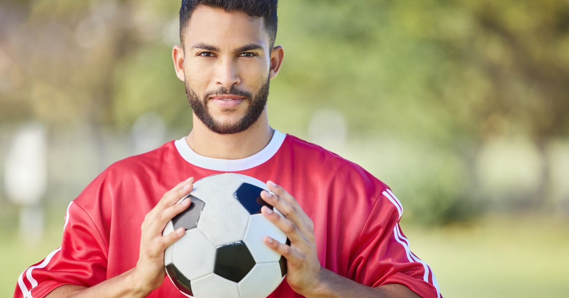 Fußballer im roten Trikot hält Ball in beiden Händen