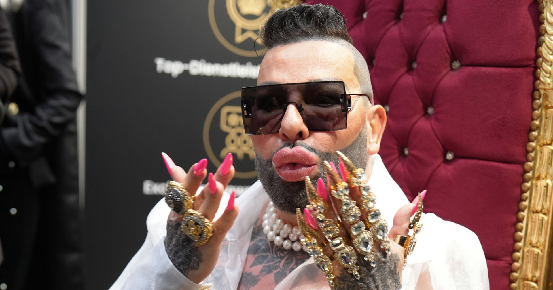 Harald Glöckler mit beschmückten Händen und pinken langen Fingernägeln. Er trägt kurze Haare und eine Sonnenbrille.