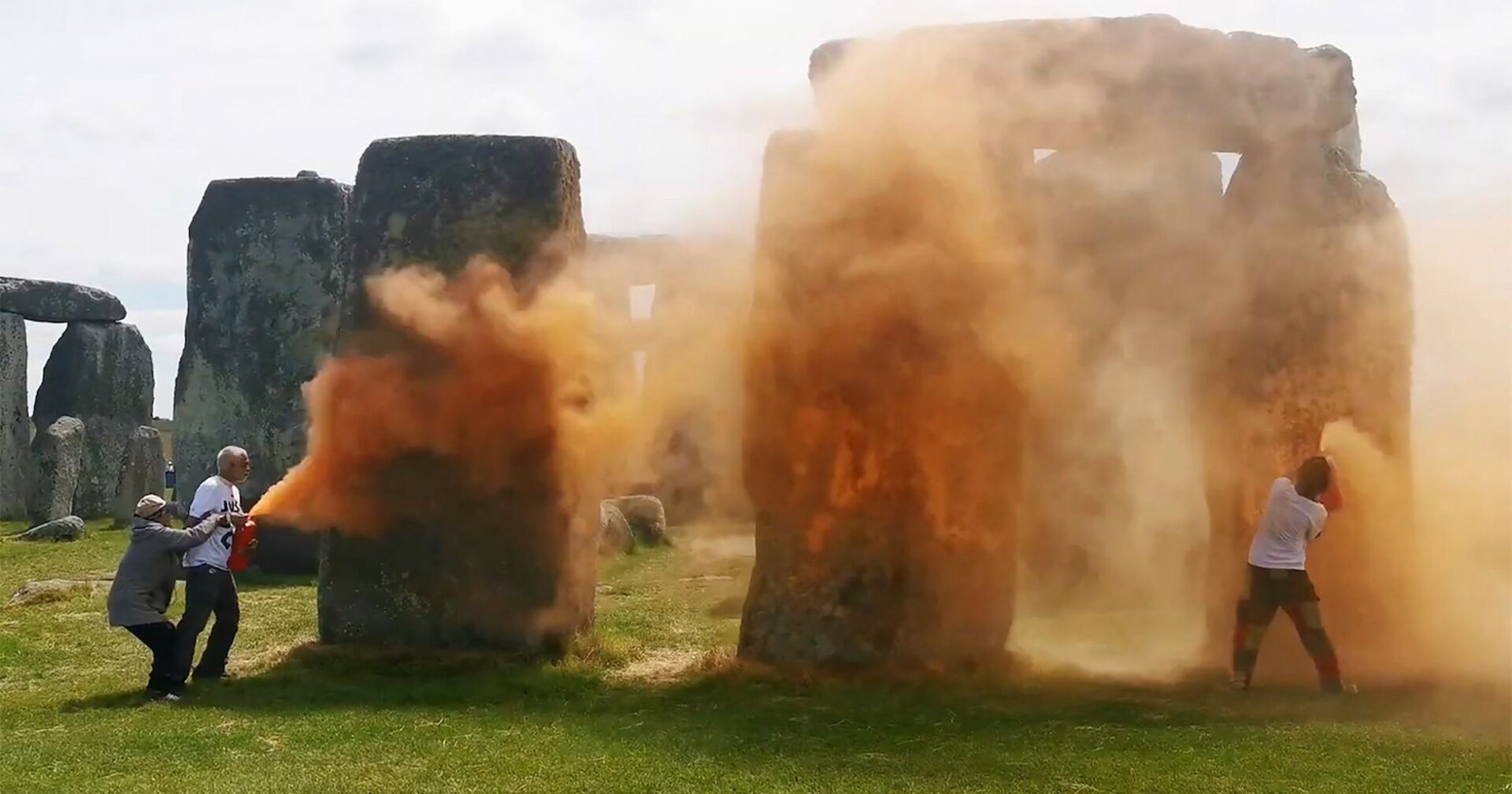 Zwei Klimaaktivisten besprühen Stonehenge mit oranger Farbe.