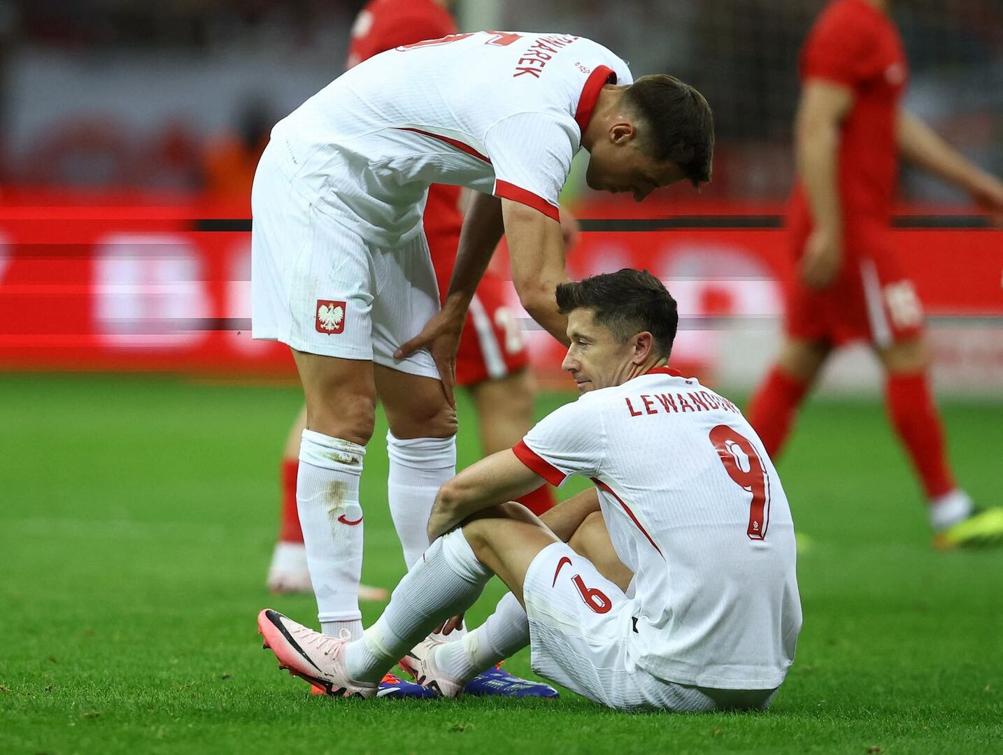 Robert Lewandowski sitzt auf dem Rasen.