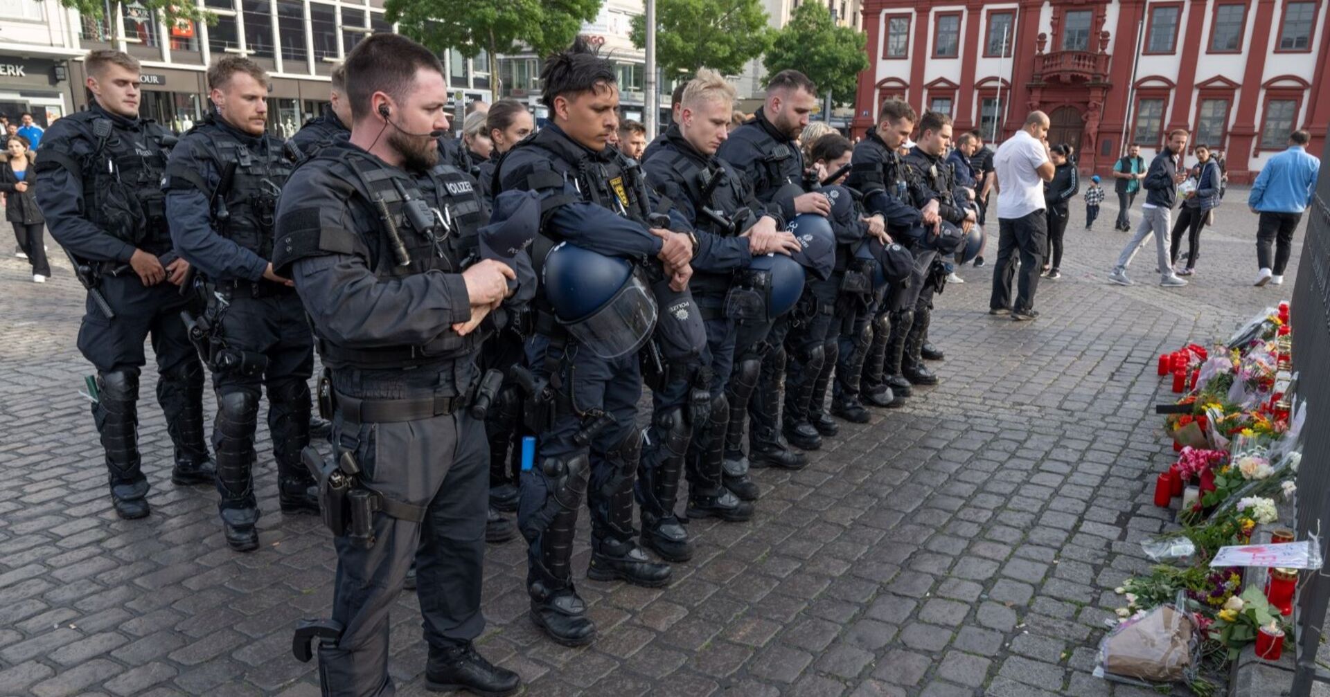 Polizisten trauern am Tatort vor niedergelegten Blumen