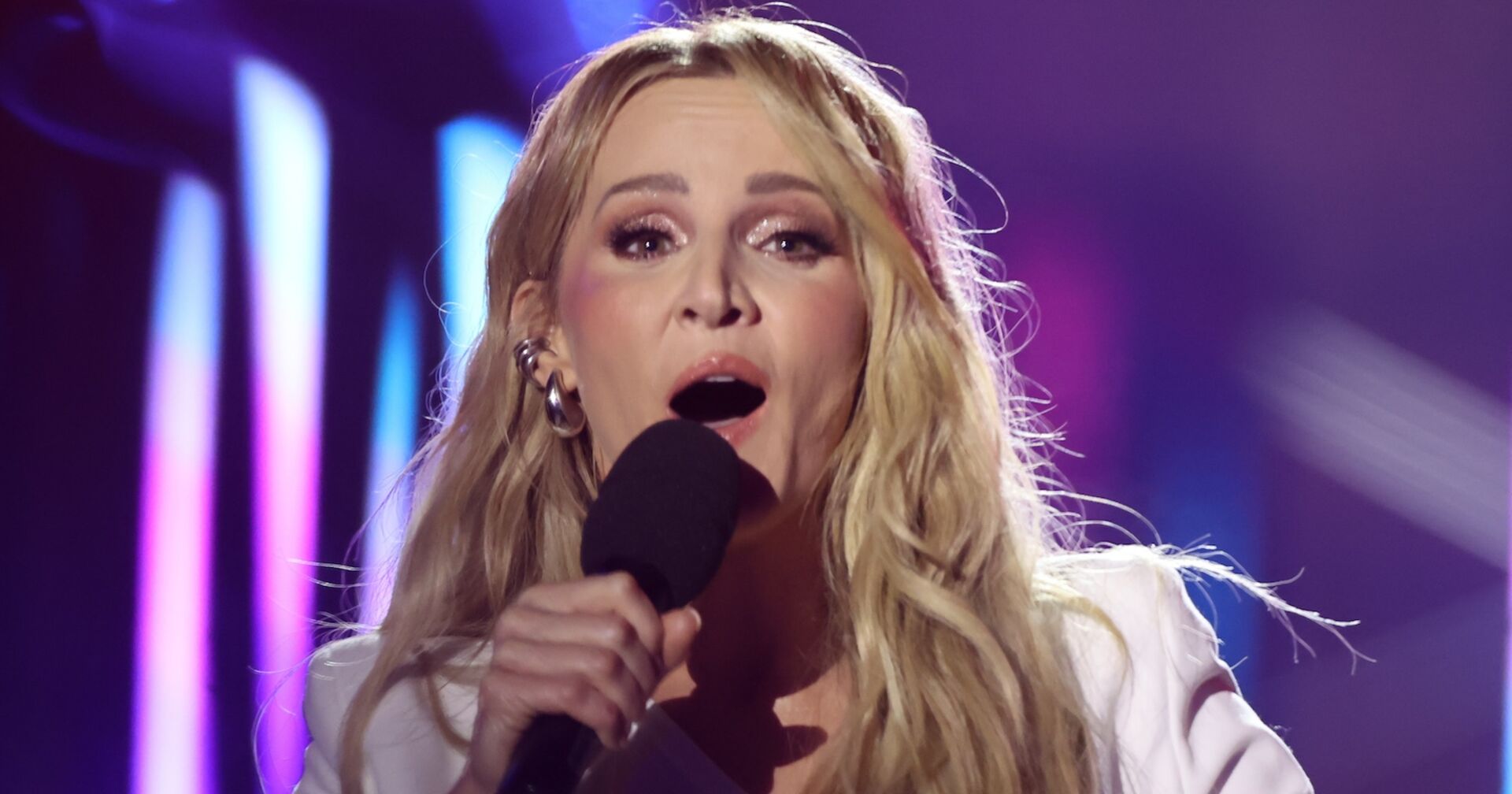 Melissa Naschenweng mit einem Mikrofon und blonden gewellten Haaren.