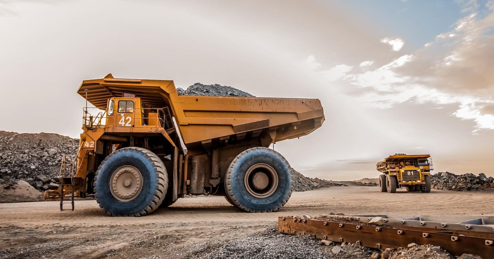 Zwei Muldenkipper auf einer Baustelle.