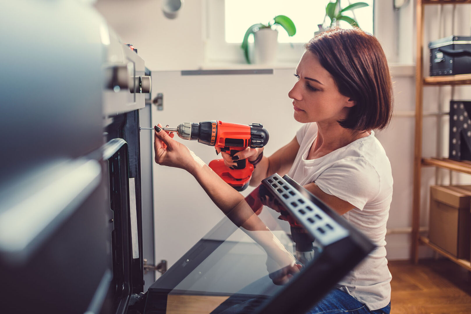 Frau repariert Küchenschrank | Credit: iStock.com/Kerkez