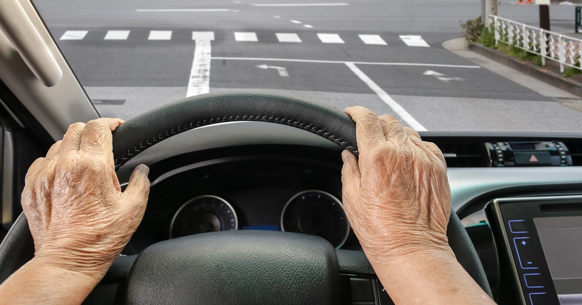 Die Hände einer Seniorin hinter dem Steuer.