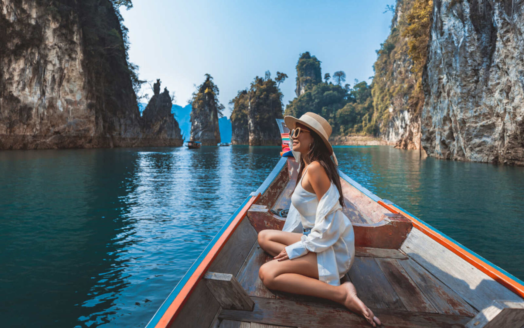 Eine Frau mit Hut sitzt auf einem Boot umgeben von kleinen Inseln