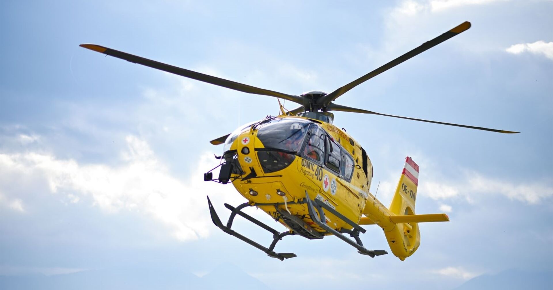 Ein gelber ÖAMTC-Rettungshubschrauber in der Luft.