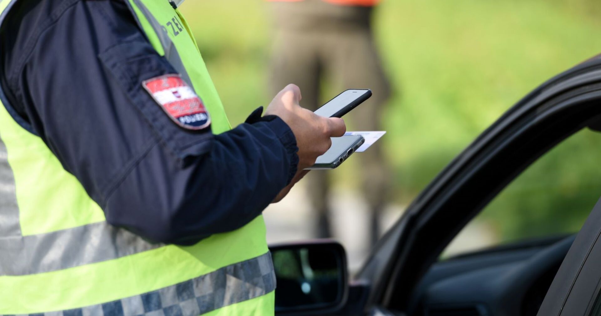 Ein Polizist kontrolliert die Identität eines Autofahrers.