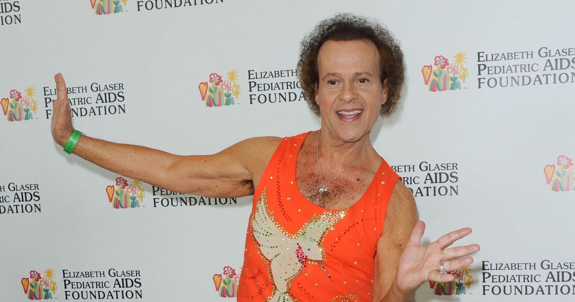 Richard Simmons, immer grinsend, wirft sich im Fitness-Outfit am Roten Teppich in Pose