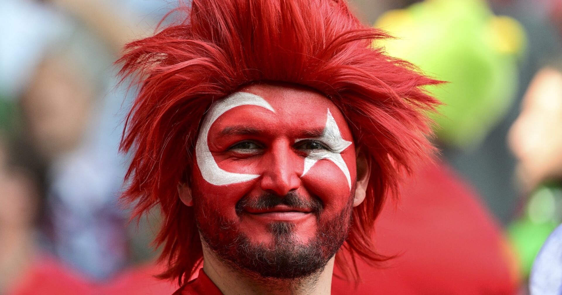 Fußballfan mit roter Perücke und den türkischen Landesfarben im Gesicht