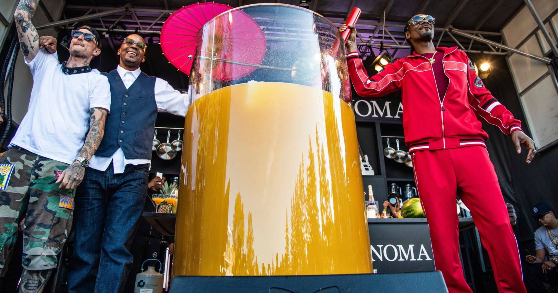 Der Rapper Snoop Dogg auf einer Bühne neben einem 500 Liter-Cocktail in einem überdimensional großen Glas samt Strohhalm