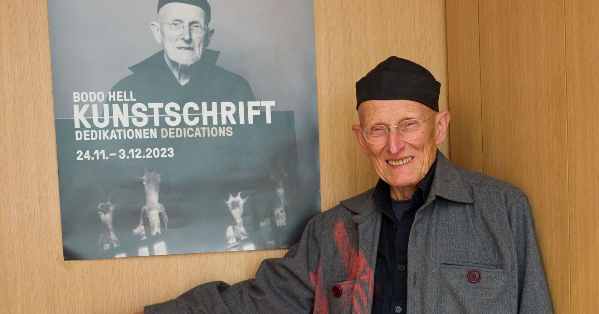 Bodo Hell vor einem Plakat, das ihn selbst zeigt.