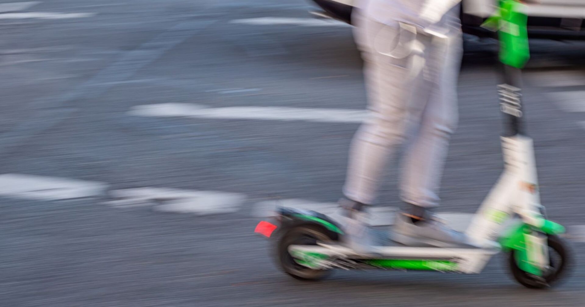 Jemand fährt mit einem E-Scooter über die Straße.
