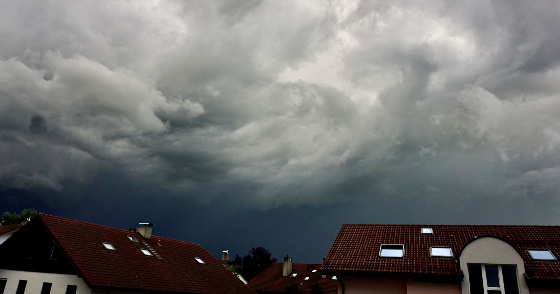 Unwetter mit dunklen Wolken zieht über eine Stadt auf.