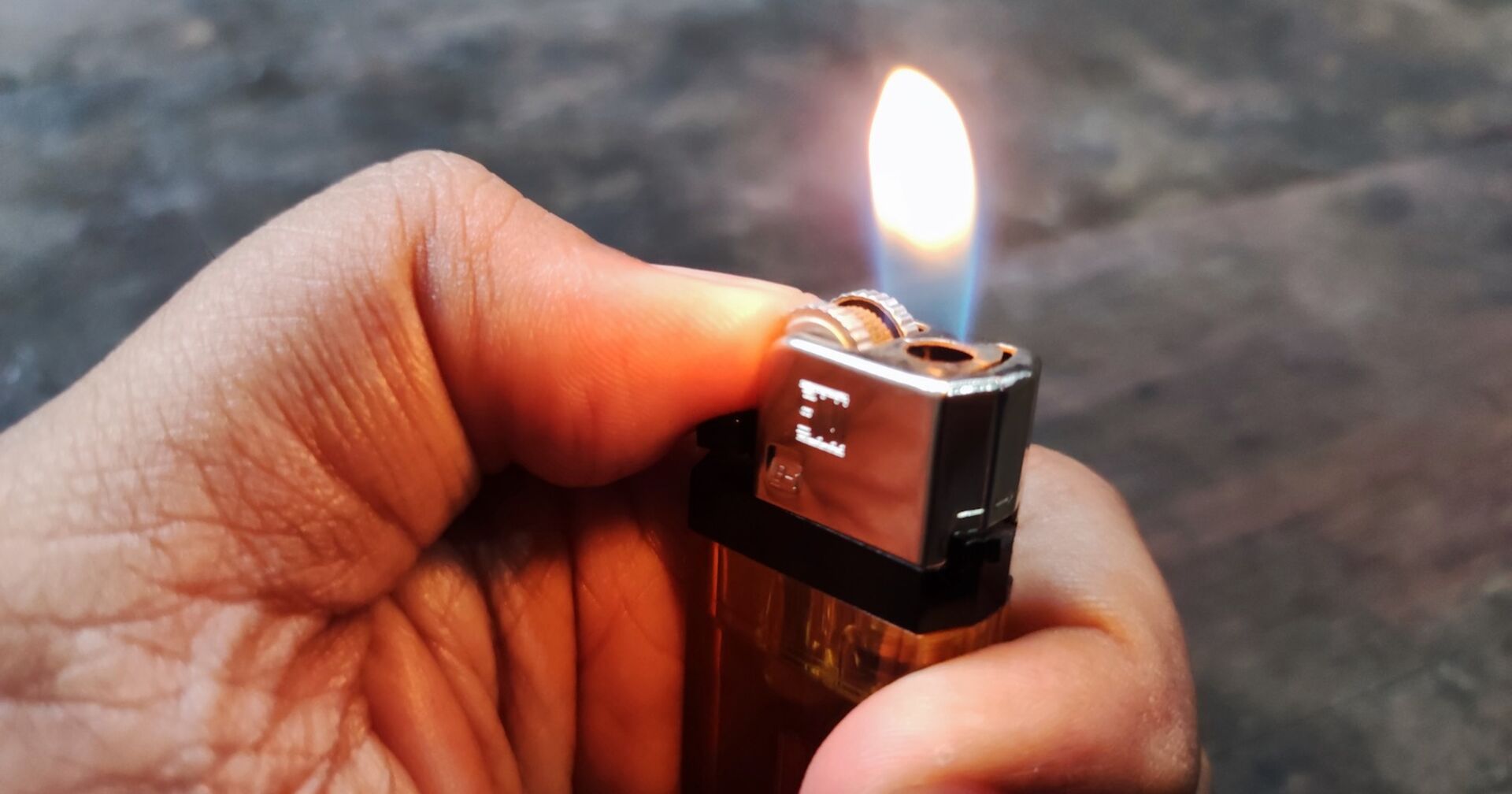 Ein Mann hält ein brennendes Feuerzeug in der Hand.