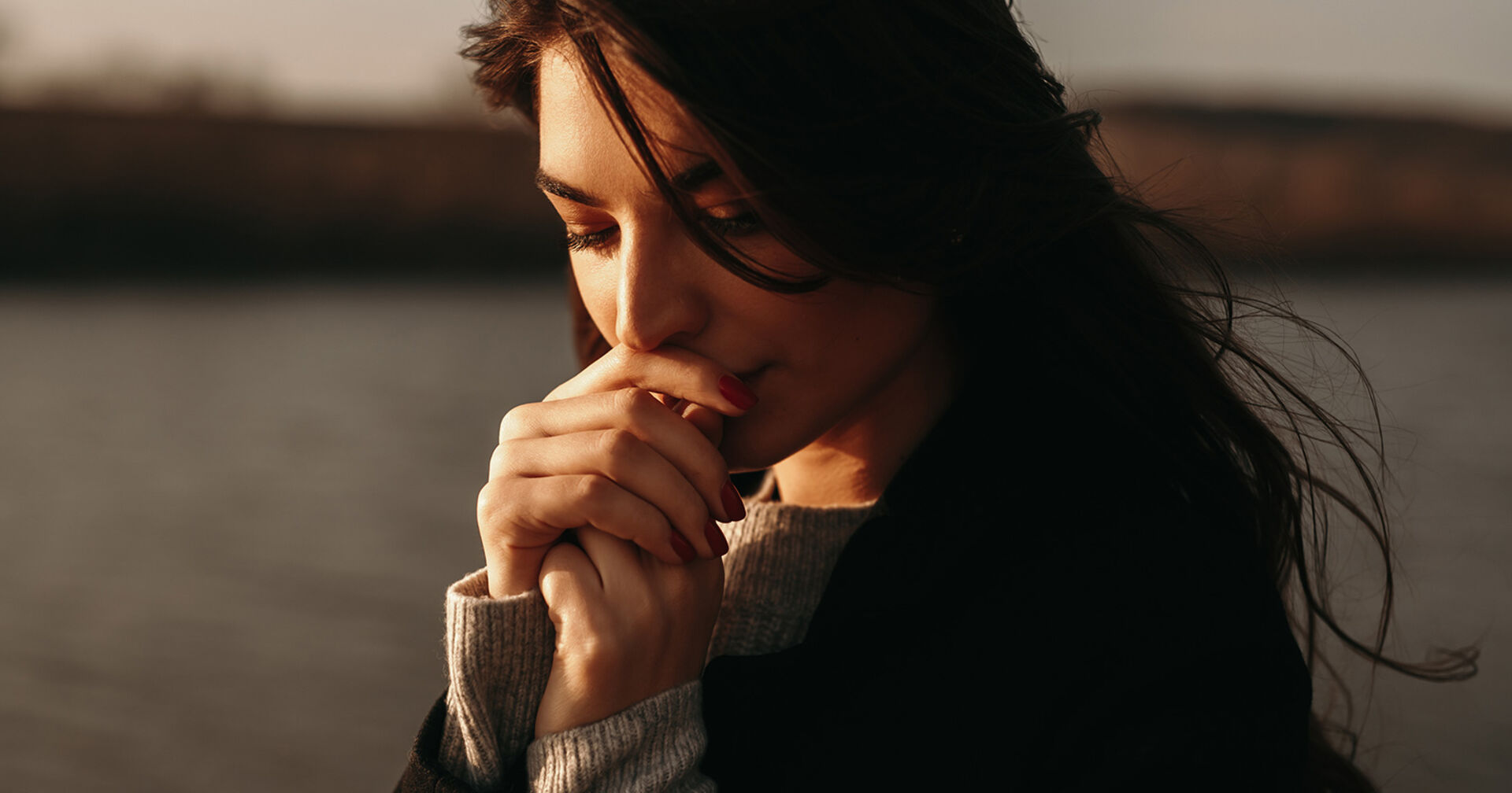 Nachdenkliche Frau am Ufer eines Sees | Credit: iStock.com/max-kegfire