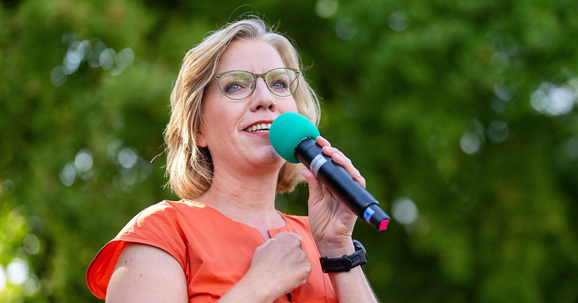 Leonore Gewessler mit Mikrofon auf einer Bühne.