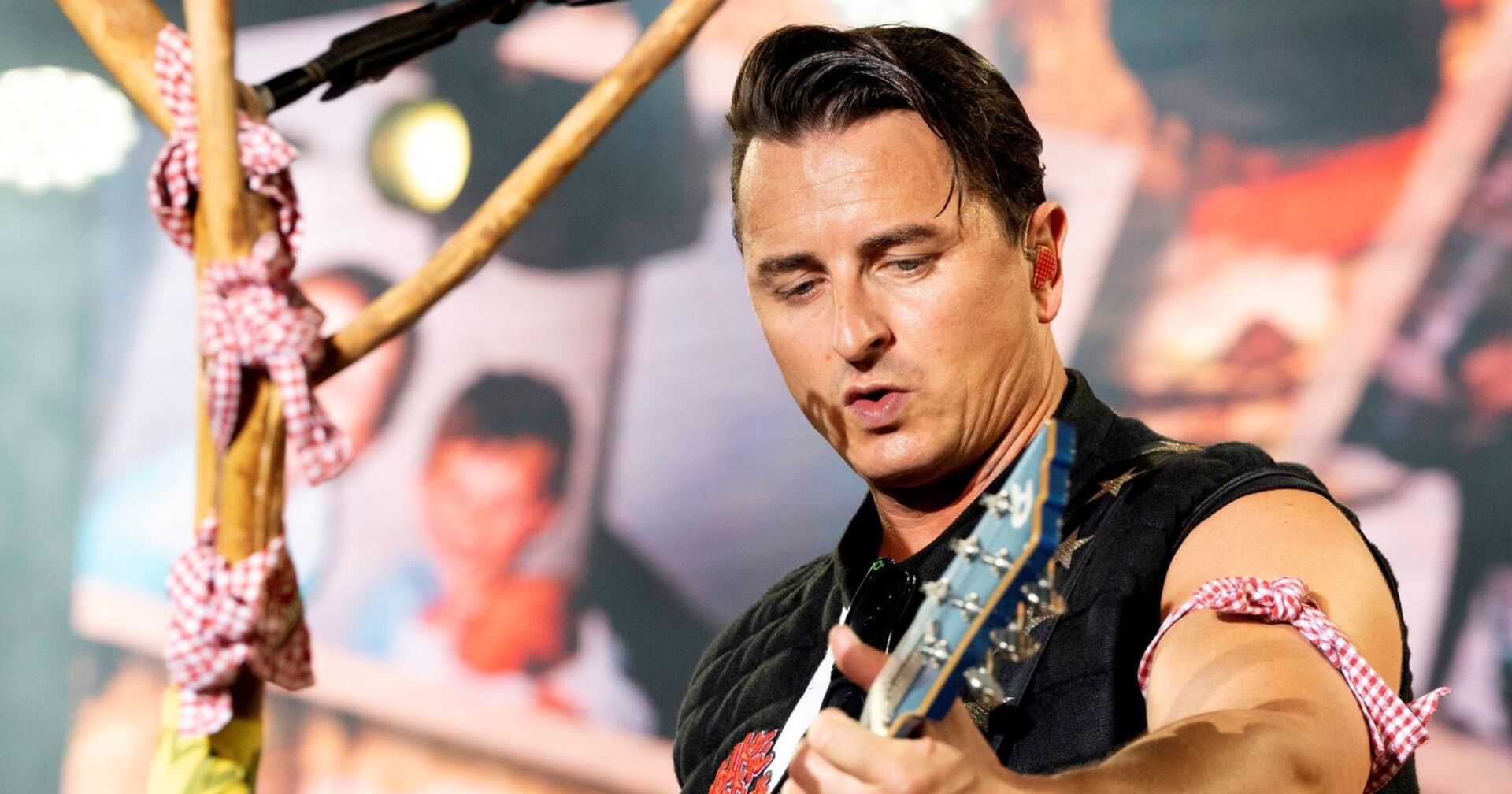Andreas Gabalier spielt Gitarre auf einer Bühne.