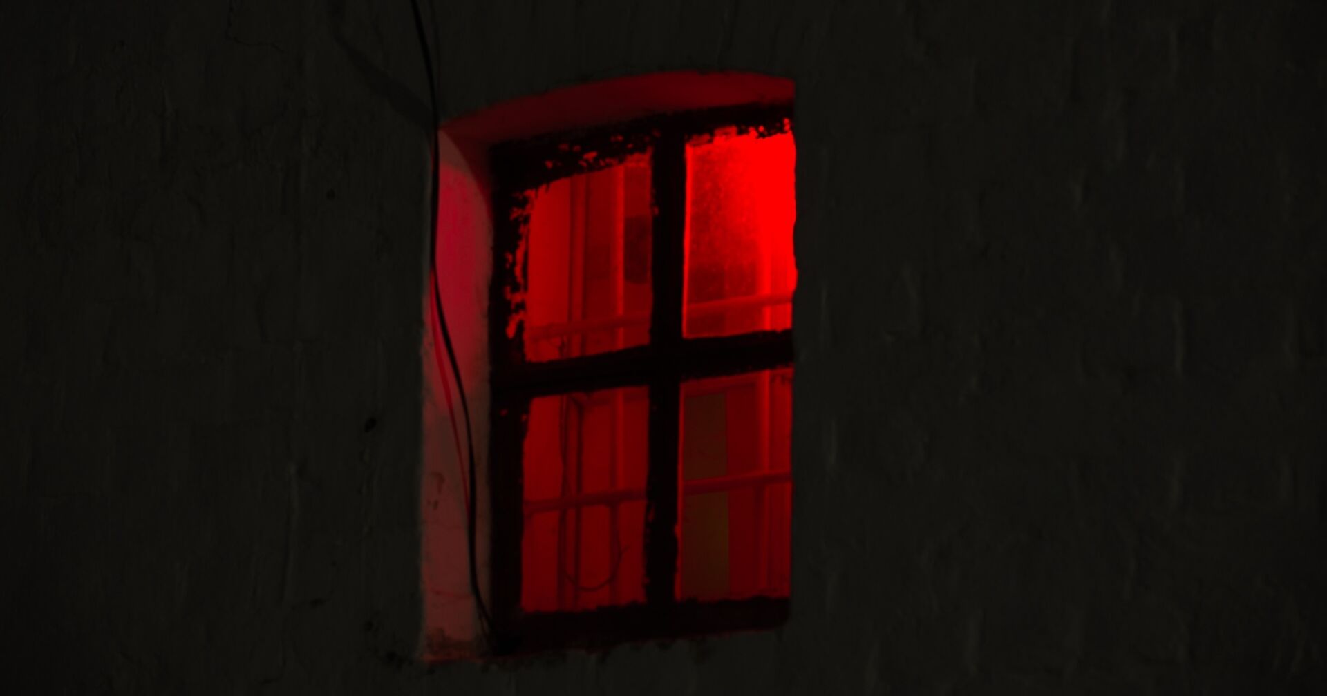 Ein Fenster in der Nacht, in dem ein rotes Licht scheint.