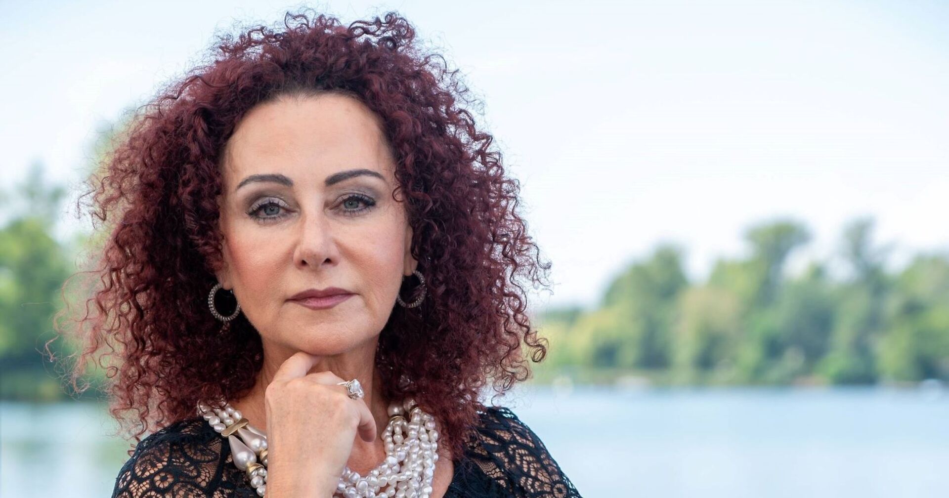 Mausi Lugner mit Perlenketten blickt ernst in die Kamera.