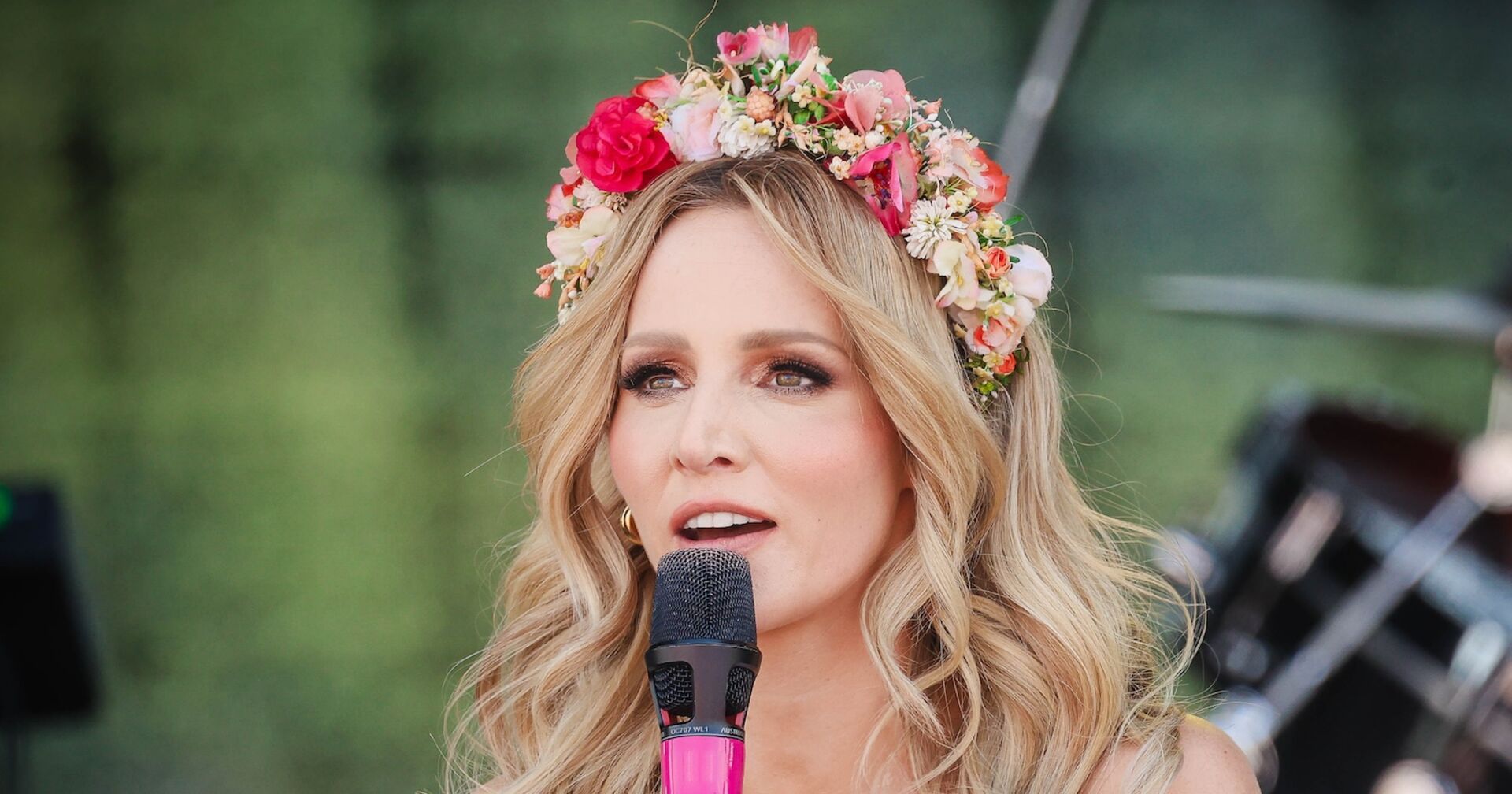 Melissa Naschenweng mit einem Blumenkranz mit einem Mikro in der Hand bei einem Auftritt