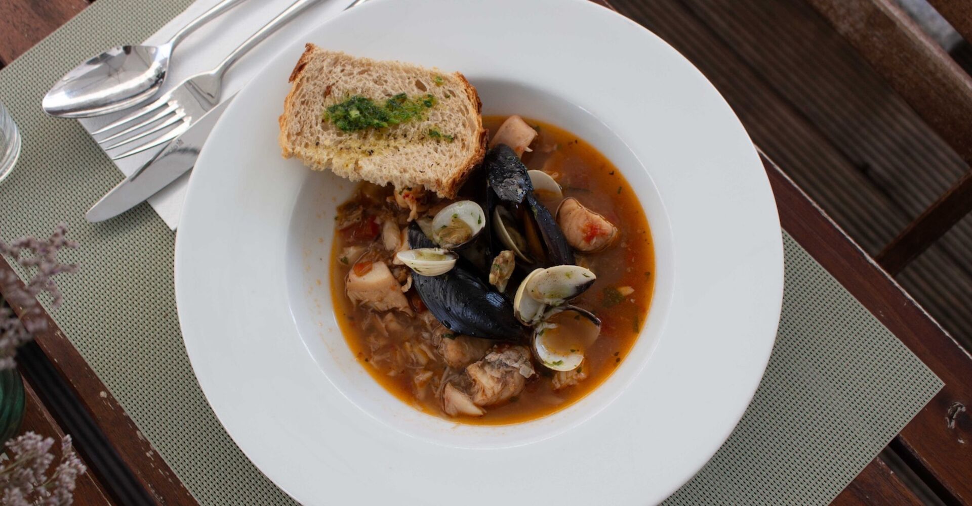 Die Fischsuppe mit Muscheln, Fischstücken und Garnele wird im Panigl mit einem Stück getoastetem Weißbrot serviert.