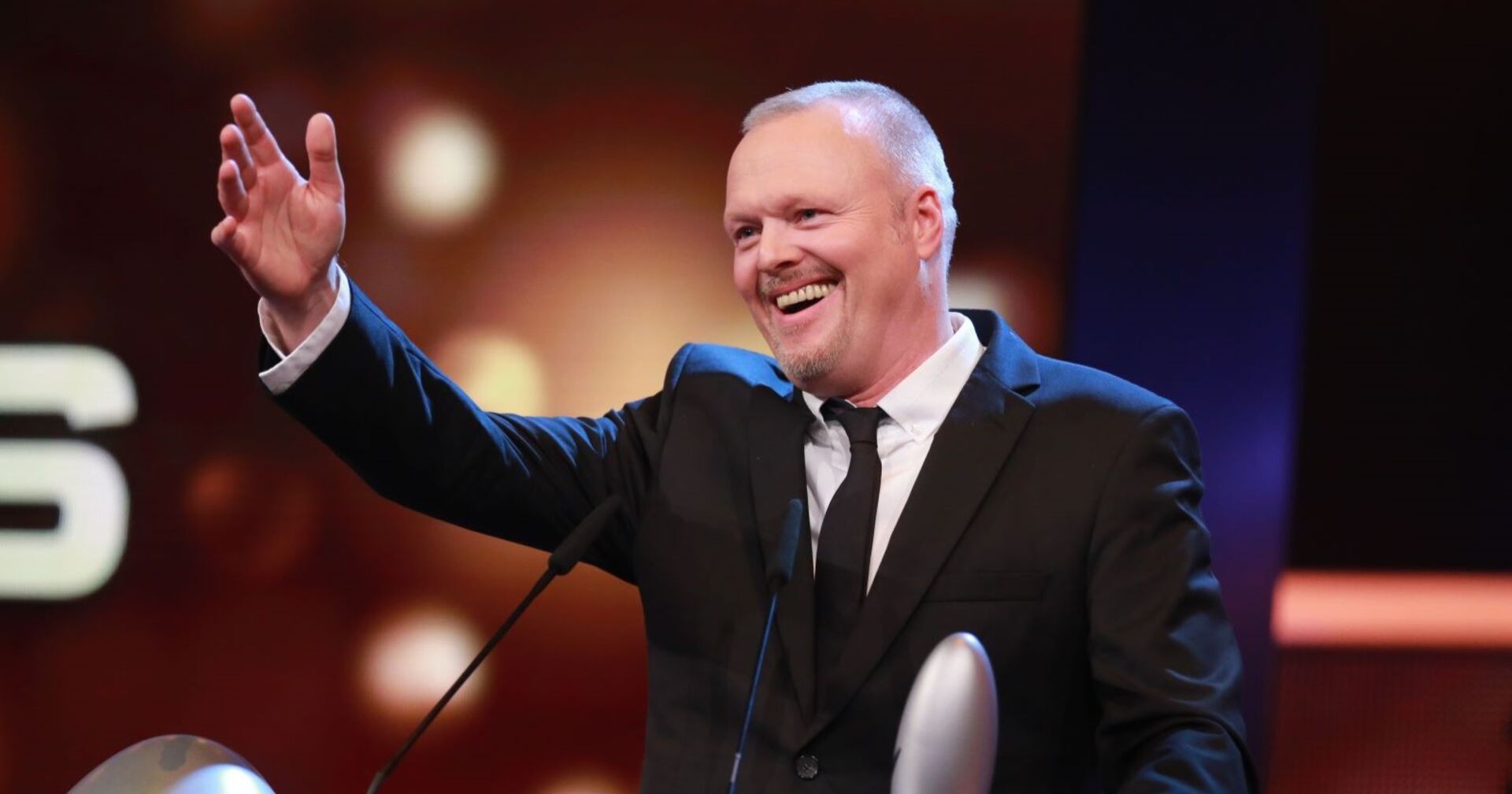 Stefan Raab spricht auf der Bühne in ein Mikrophon.
