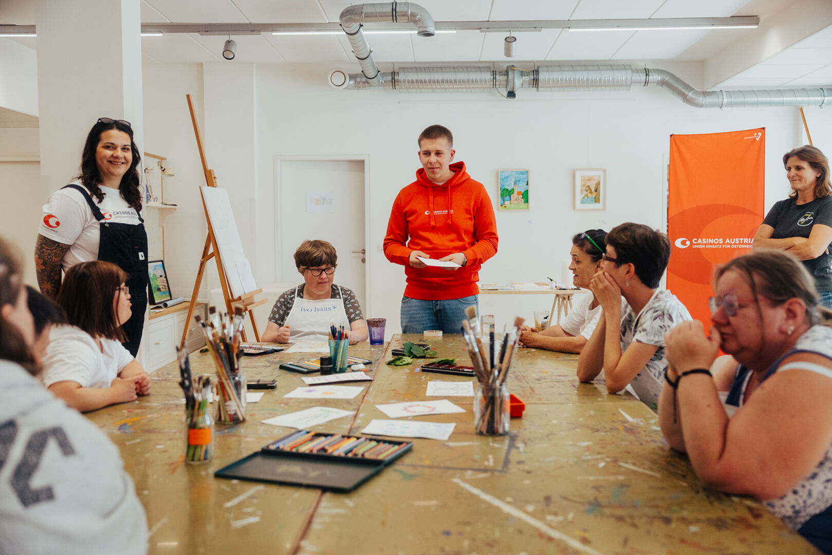 Zwei Frauen und ein Mann kümmern sich um eine Gruppe hilfsbedürftiger Menschen | Credit: Casinos Austria