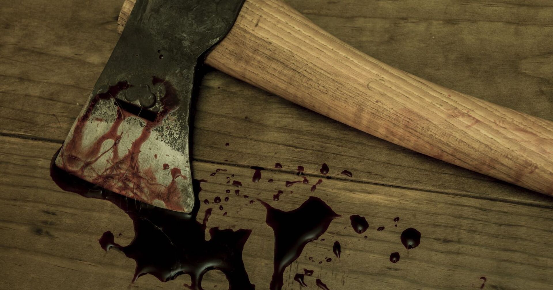 Eine blutige Axt auf einem Holztisch.