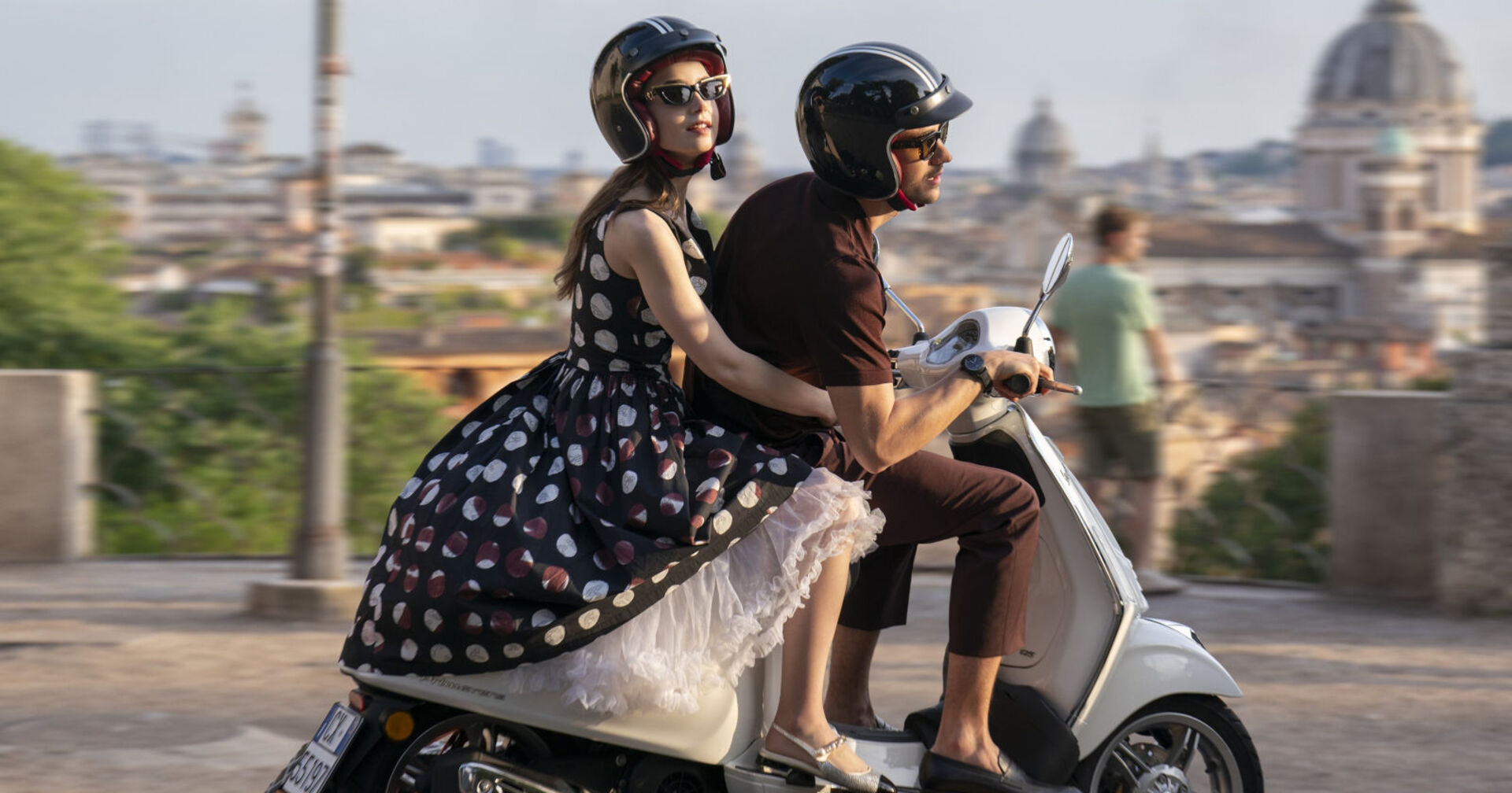 Frau fährt mit einem Mann gemeinsam auf einer Vespa durch eine Stadt