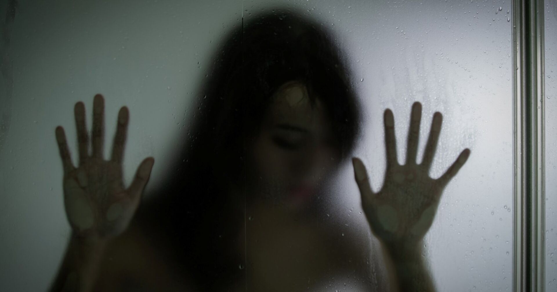 Silhouette einer Frau hinter einer Glasscheibe.