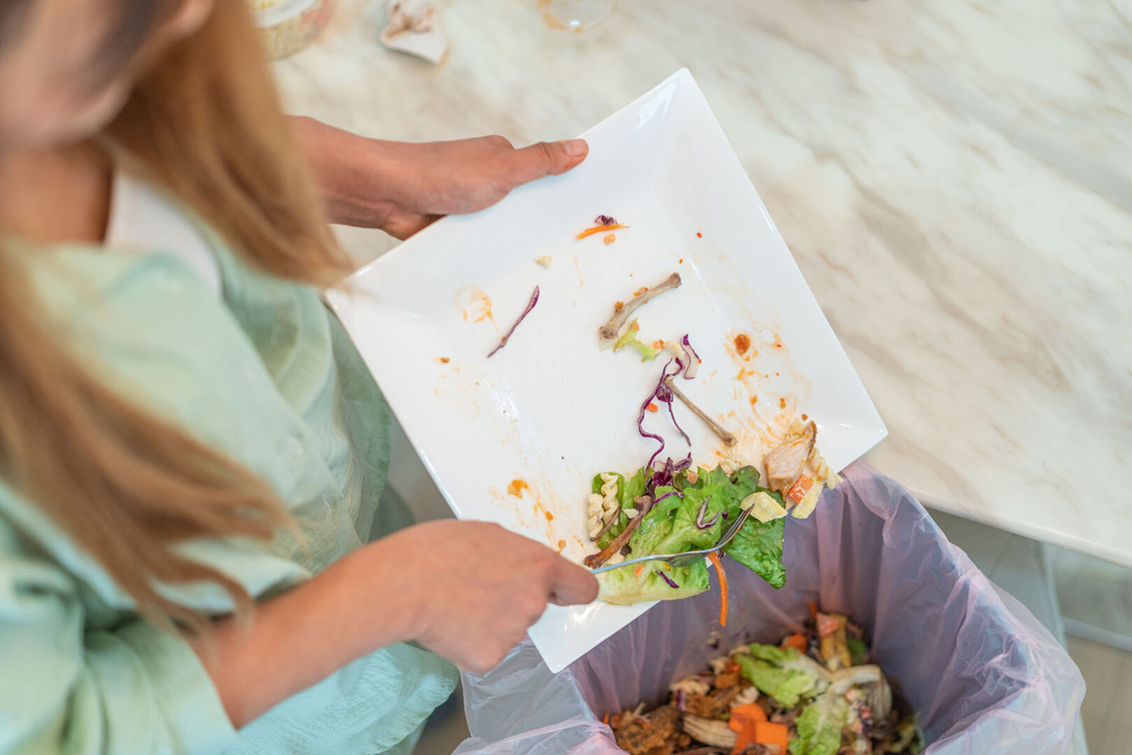 Frau wirft Lebensmittelreste in den Müll | Credit: iStock.com/6AM