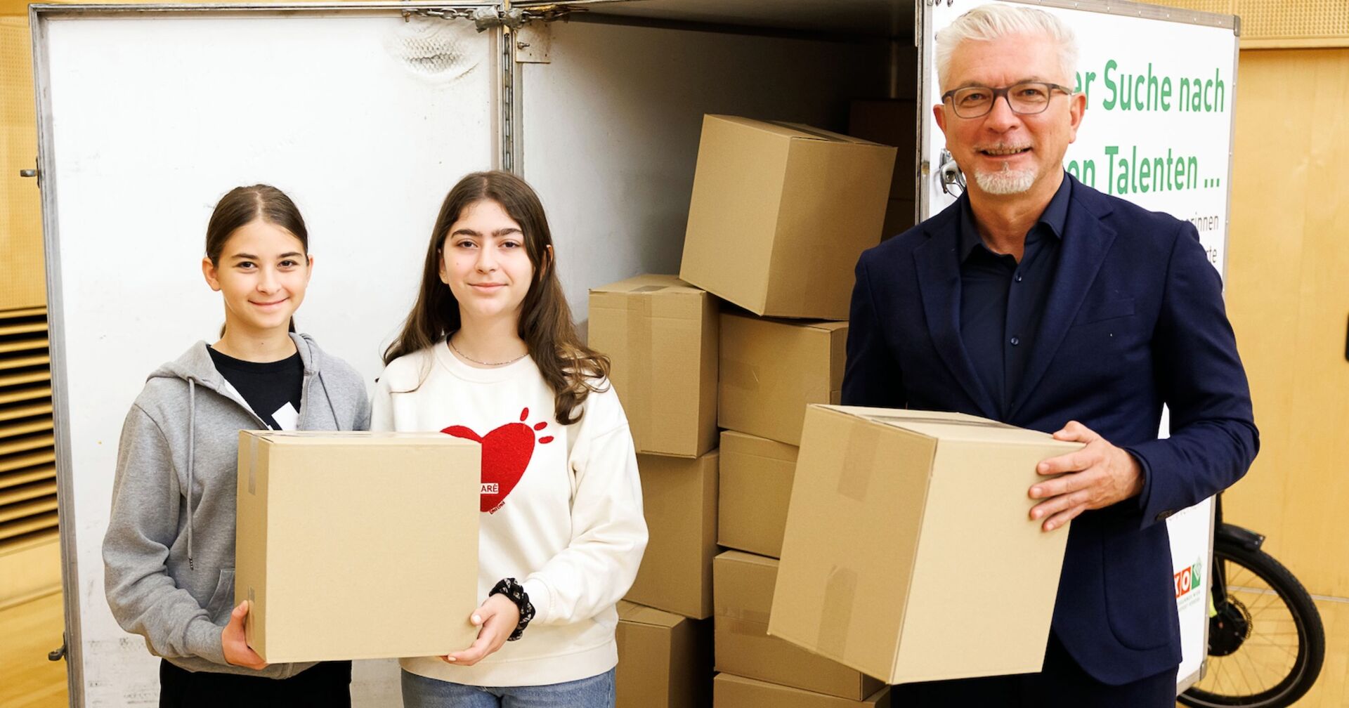 Mann und zwei Jugendliche mit Kartons in den Händen