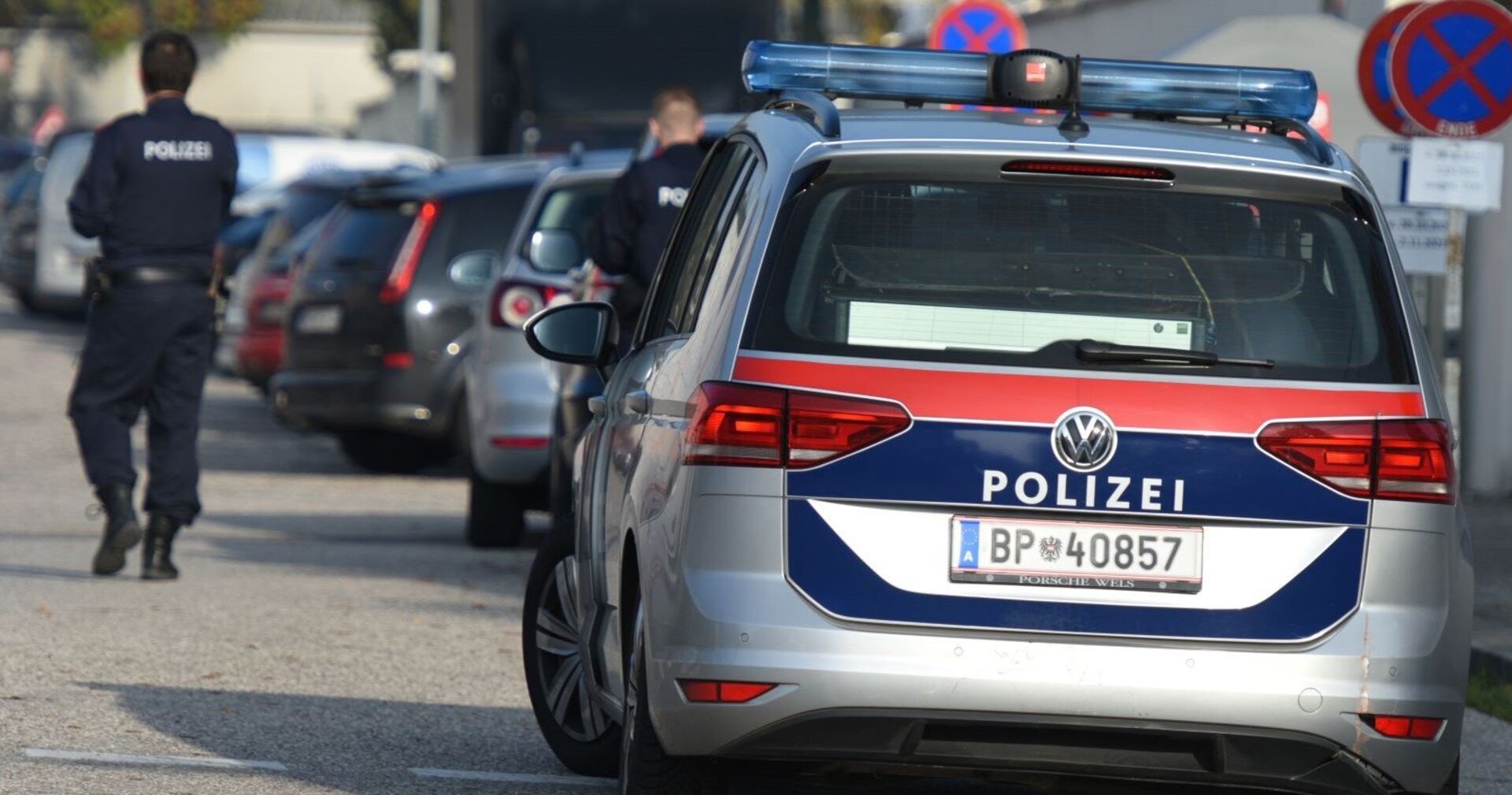 Ein Polizist und ein Polizeiauto auf einer Straße.